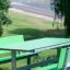 Green Table HPL with green benches in a park setting.