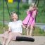 Woman and child on a Single Swing BNS 90cm in a playground.