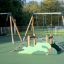 Single Swing (BNS 90cm) on playground with climbing structure nearby.