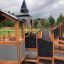 Wooden Campanille playground castle with slides and climbing structures in a park.