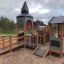 Campanille playground castle with slides and climbing features in a park.