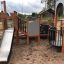 Campanille playground castle with slide and climbing structures on sandy surface