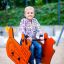 Child playing on Bulldozer rocking in playground.