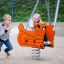 Children playing on a Bulldozer rocking spring rider in a playground.