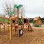 Britta's Playhouse outdoor wooden play structure with slide, climbing net, and colorful playhouse in
