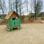 Children playing on Britta's Playhouse wooden playset with climbing wall and slide.