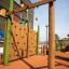 Spillikins wooden playhouse climbing wall and hanging bar in outdoor playground.