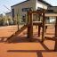 Wooden playhouse 'Spillikins' with slide and climbing structure on playground.