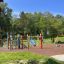 Colorful pencils-themed playground with wooden playhouse and slide in a park.
