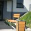 Outdoor bench and Ryga Bin Light on a sidewalk near a building.