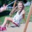 Double Safety Seat double swing with children playing in the background