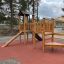 Triangle Modern Nature wooden playhouse with slide in a playground.