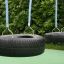 Wooden Tire double swing with black tires and blue ropes in a playground setting
