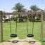 Wooden Tire double swing in a park with palm trees in the background.