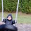 Child sitting on a Wooden Tire double swing in a playground.
