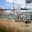 Ryga Deco Bench in a modern outdoor seating area with wooden benches and sunshade structures.