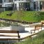 Park seating area featuring Ryga Bench w/ Backrest and other benches in a modern residential setting