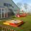 Sandbox for kids next to a playhouse with a slide in a playground.