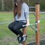 Girl using Bars II outdoor fitness equipment.