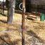 Wooden climbing post with metal handles in a playground.