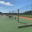 Outdoor playground exercises Handles on green surface with fences in background.