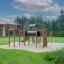 Playground structure Romping Cottage with slides, climbing nets, and swings in a residential backyar
