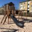 Wooden Romping Cottage playground with slide and climbing elements.