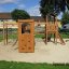 Wooden playground set Romping Cottage with climbing nets and slides in a park.