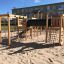 Wooden playground structure with climbing nets and a tunnel slide, Romping Cottage.