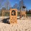 Wooden playground structure Romping Cottage with climbing wall and sand flooring.