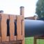 Wooden playground tunnel from Romping Cottage in a park.