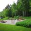 Outdoor workout station with wooden benches and bars, Product Platform 180, surrounded by lush green