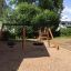 Swing Frame 1(BNS) +1 (double swing) playground equipment in a backyard with sand and green trees.