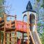 Alcazar playground castle with slide and climbing structure in a park.