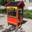 Playhouse for children in a playground with red and yellow panels and a black roof