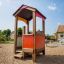 Wooden Playhouse for children on a sandy playground.