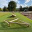 Wooden Balancer playground equipment on green artificial grass.