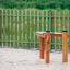 Xylophone playground equipment in a sandy play area with a wooden fence in the background.