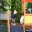 Children playing on Playhouse wooden playground with climber slide.