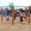 Children playing on Six Arm Swing Nature (multiple swing) playground equipment decorated with balloo