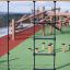 Ural climbing net on an outdoor playground with wooden structures in the background.