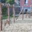 Ural climbing net in a playground with wooden posts on a sandy surface.