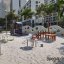Villa sandbox with a playhouse in a modern playground with trees and buildings in the background.