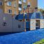 Playground steamboat ship with slide on blue rubber surface in residential area.