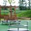 Bench around the tree made of wood and metal on a playground with green safety flooring.