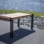 Thor table with metal legs and wooden top set by a riverside.