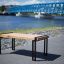 Thor table with black metal legs and wooden top placed by the river.