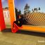 Modern playground equipment Ribbon Fitness II in orange with a person sitting on it.
