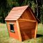 Wooden playhouse Crooked House on a grassy field.