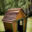 Wooden playhouse named Crooked House in a garden.